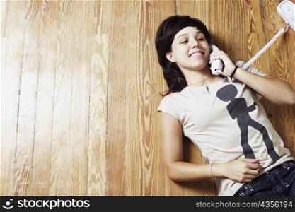 High angle view of a young woman lying on the floor and talking on the telephone