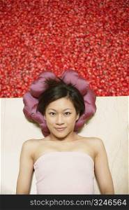 High angle view of a young woman lying on the floor near a hot tub filled with rose petals