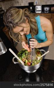 High angle view of a young woman preparing salad in the kitchen