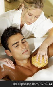 High angle view of a young woman scrubbing a young man&acute;s chest with a bath sponge