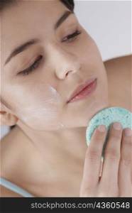 High angle view of a young woman scrubbing her chin with a sponge