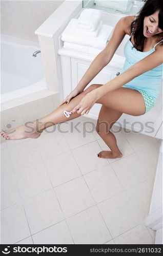 High angle view of a young woman shaving her leg with a razor
