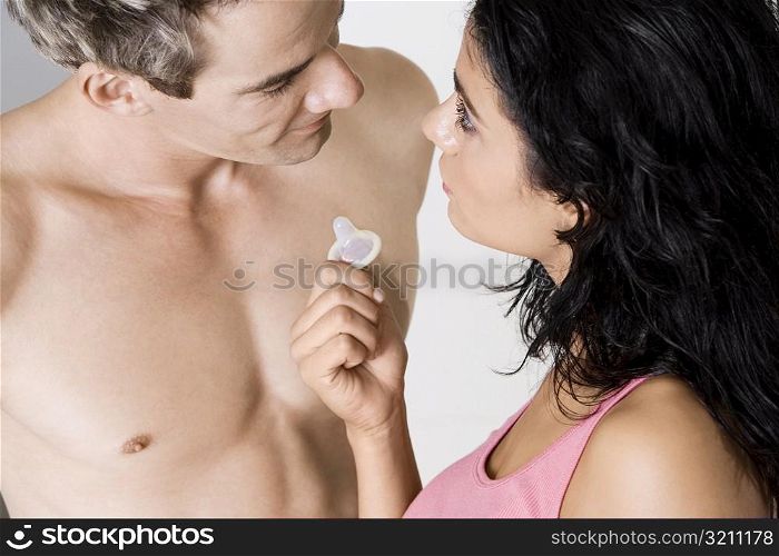 High angle view of a young woman showing a condom to a mid adult man