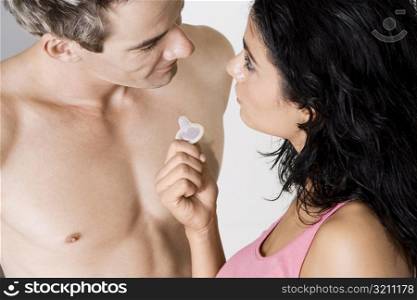 High angle view of a young woman showing a condom to a mid adult man