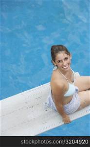 High angle view of a young woman sitting on a diving board