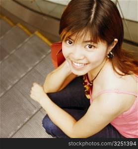 High angle view of a young woman sitting on an escalator smiling