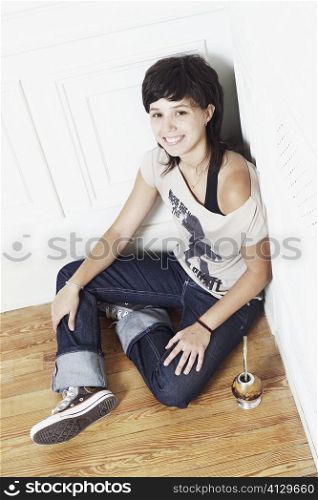 High angle view of a young woman sitting on the floor at the corner of a room