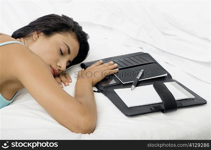 High angle view of a young woman sleeping on a bed with a personal organizer