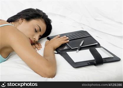 High angle view of a young woman sleeping on a bed with a personal organizer