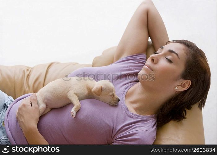High angle view of a young woman sleeping on a couch with a puppy on her