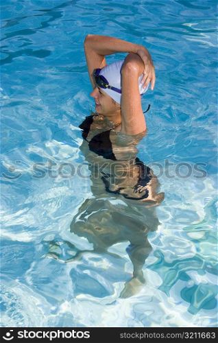 High angle view of a young woman standing in a swimming pool and smiling