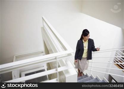 High angle view of a young woman standing on a staircase and holding a mobile phone