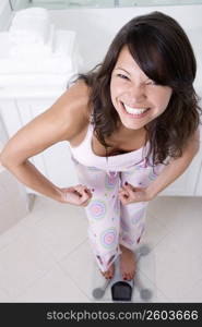 High angle view of a young woman standing on a weighing scale