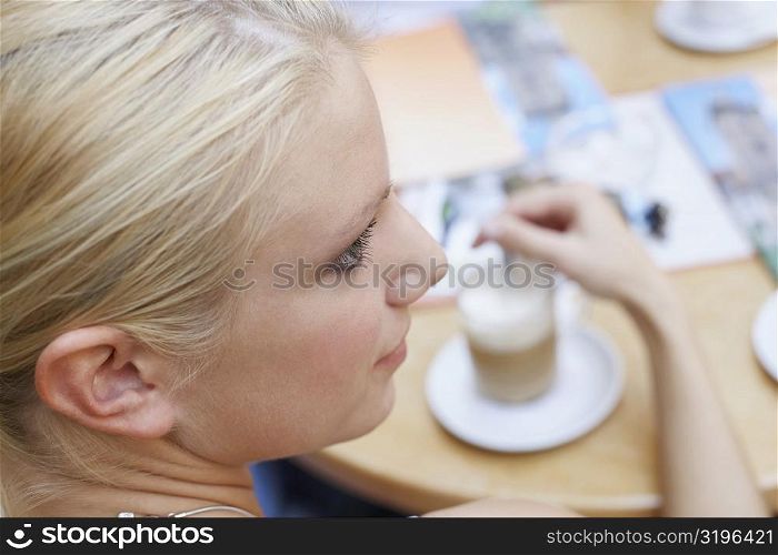 High angle view of a young woman stirring coffee