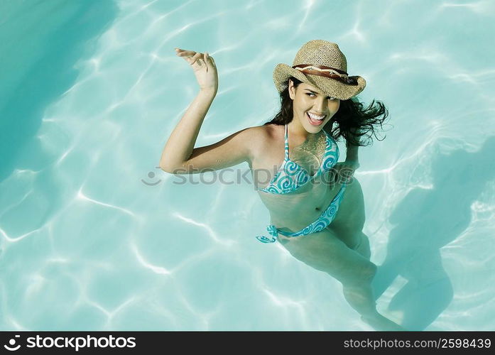 High angle view of a young woman swimming in a pool and smiling