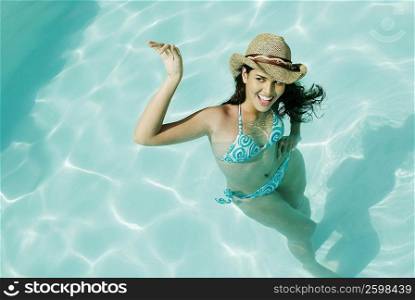 High angle view of a young woman swimming in a pool and smiling