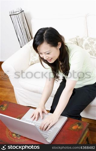 High angle view of a young woman using a laptop and smiling
