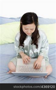 High angle view of a young woman using a laptop on the bed