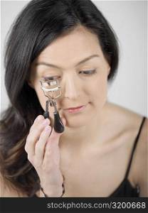 High angle view of a young woman using an eyelash curler