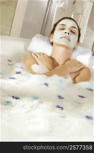 High angle view of a young woman wearing a facial mask in a bathtub