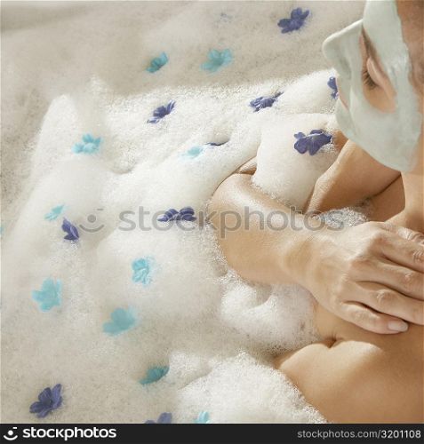 High angle view of a young woman wearing a facial mask in a bathtub