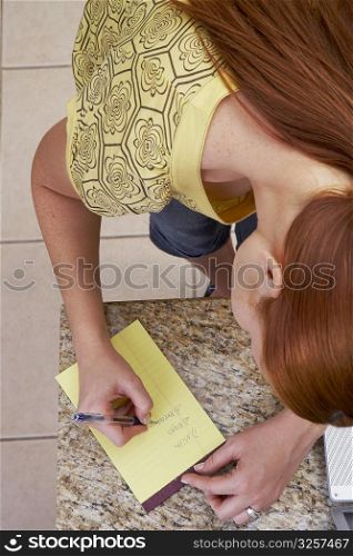 High angle view of a young woman writing on a notepad
