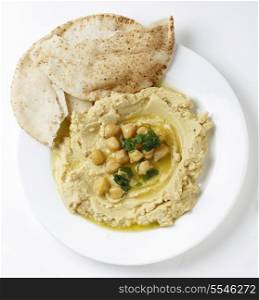 High angle view of Arab masbacha, hummus dip served with whole chickpeas and a chilli and lemon flavoured sauce and unleavened bread.