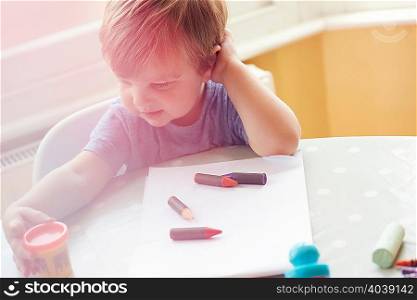 High angle view of boy sitting at table with art supplies