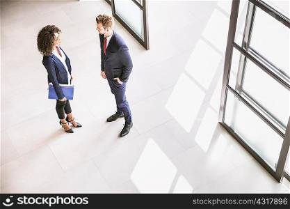 High angle view of businessman and woman talking at office entrance