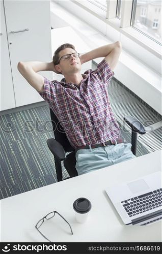 High angle view of businessman relaxing at desk in creative office