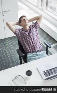 High angle view of businessman relaxing at desk in creative office