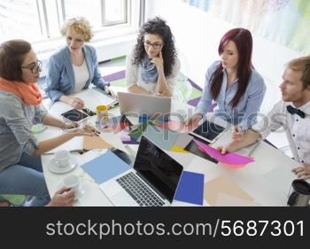High angle view of businesspeople analyzing photographs in creative office