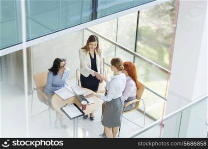 High angle view of businesswomen shaking hands at table in office