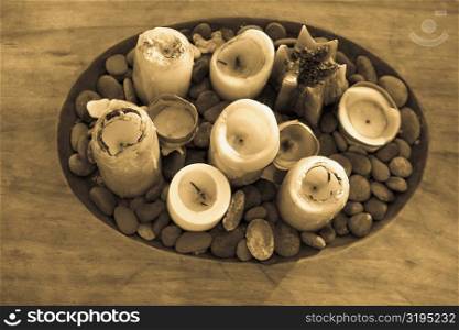 High angle view of candles and pebbles in a wooden tray