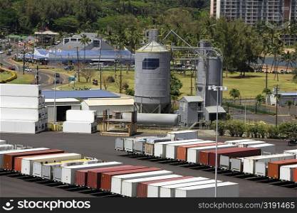 High angle view of cargo containers and a storage tank at a commercial dock