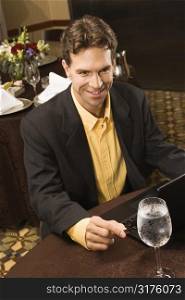 High angle view of Caucasian businessman with laptop in restaurant.