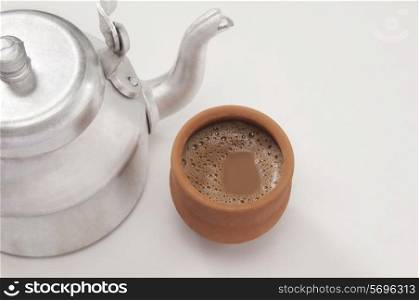High angle view of chai in traditional cup made of mud with tea kettle isolated over white background