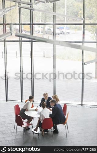 High angle view of colleagues planning during meeting while sitting at table in office