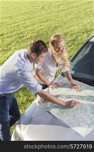 High angle view of couple reading map on car hood during road trip