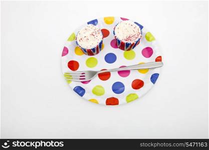 High angle view of cupcakes in multicolored plate against white background