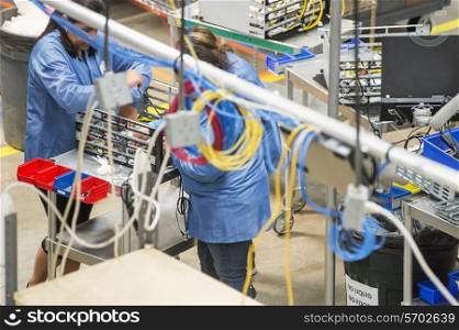 High angle view of female technicians repairing computer part in electronics industry
