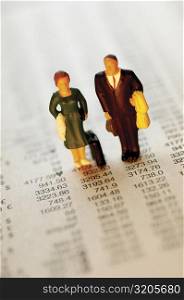 High angle view of figurines of a businessman and a businesswoman on a sheet of financial figures