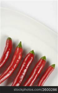 High angle view of five red chili peppers in a plate