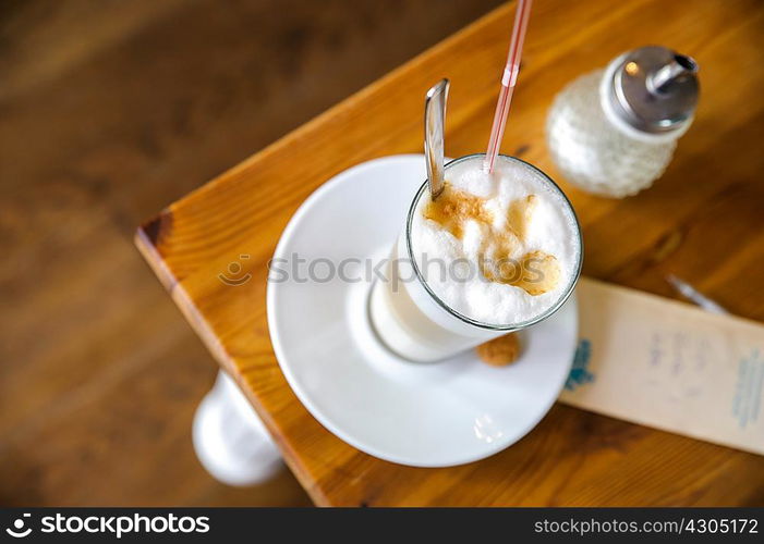 High angle view of frothy latte and sugar dispenser on table