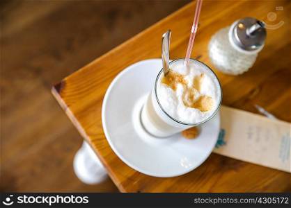 High angle view of frothy latte and sugar dispenser on table