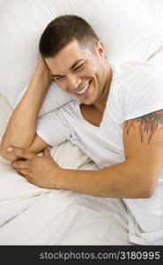 High angle view of handsome Caucasian mid adult man lying in bed smiling.