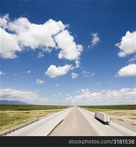 High angle view of highway with tractor trailer truck and blue cloudy sky.
