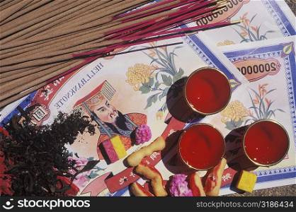 High angle view of incense sticks with bank notes and candles