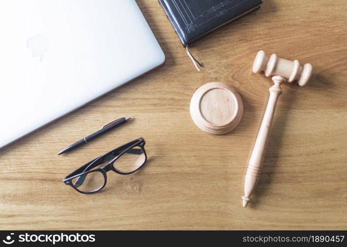 high angle view of laptop spectacles gavel and pen on wooden background on wooden desk