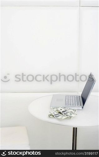 High angle view of laptop with dollar bill on the table